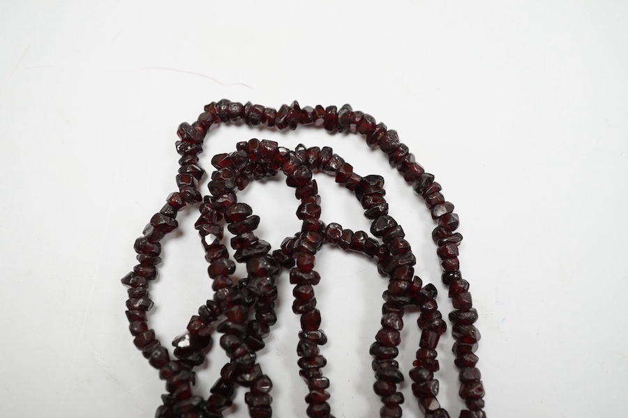 A late 19th/early 20th century multi strand rough cut garnet set necklace, with a yellow metal mounted oval cameo shell clasp, 43cm. Condition - poor to fair